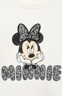 Bijela dukserica s izvezenim likom koji nosi mašnu s cvjetnim uzorkom i riječ "MINNIE" u tamnom cvjetnom dizajnu.