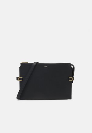 Sac bandoulière rectangulaire noir avec une fine sangle réglable, des boucles dorées, une fermeture éclair supérieure et un petit logo Fossil au centre avant.