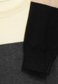 Rundhalssweater med färgblock i beige, svart, mörkgrå och kräm, med en ribbad svart mudd.