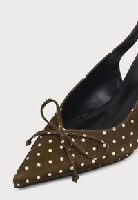 Chaussure slingback marron pointue à pois blancs avec un nœud noué à l'avant, dotée d'une doublure intérieure noire.