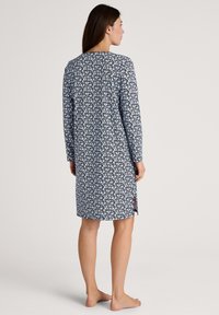 Navy blue floral nightdress with long sleeves, round neckline, and side slits, made of soft fabric. Features a white flower pattern throughout.