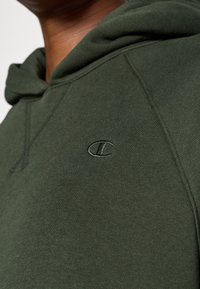 Hanorac verde realizat dintr-un material moale cu o textură ribbed. Dispune de un mic logo brodat pe piept și un design clasic al glugii.