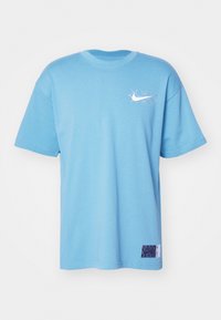 Světle modré bavlněné tričko s kulatým výstřihem, krátkými rukávy a bílým logem Nike na hrudi. Na spodním lemu má texturovanou nášivku.