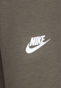 Vêtements de sport en mélange de coton vert avec une finition texturée, arborant un logo Nike blanc en évidence sur le devant.