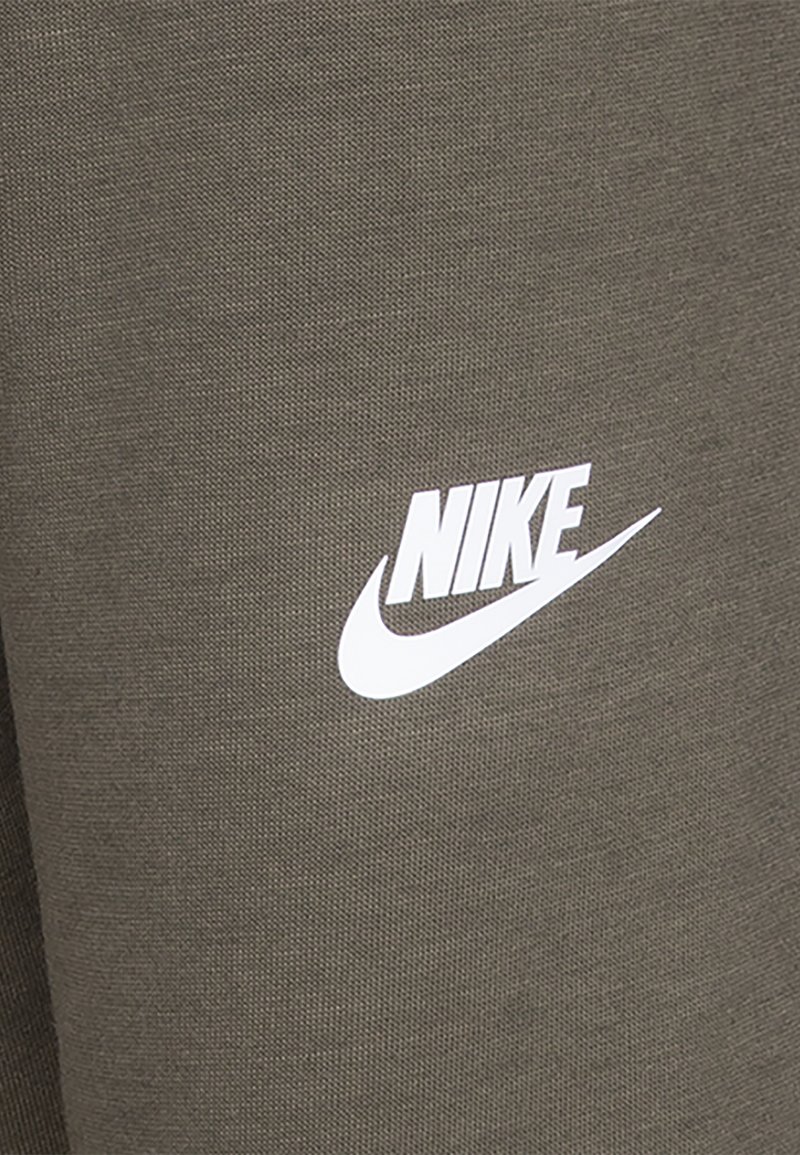 Vêtements de sport en mélange de coton vert avec une finition texturée, arborant un logo Nike blanc en évidence sur le devant.