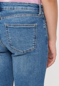 Mid-rise blå denimjeans med rett snitt, med baklomme, synlig søm og en glatt tekstur.