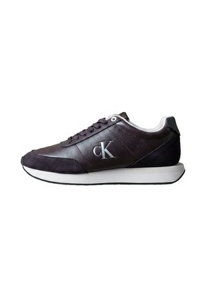 Baskets en cuir et suède brun foncé avec une semelle et des lacets blancs, avec le logo "cK" sur le côté.