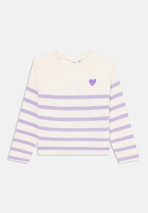 Chemise à manches longues en crème avec des rayures horizontales lavande. Présente un petit cœur violet sur la poitrine. Tissu en coton doux, col ras du cou.