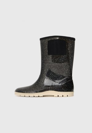 Black speckled mid-calf rubber boot with beige treaded sole and black textured pull tab on smooth waterproof surface.