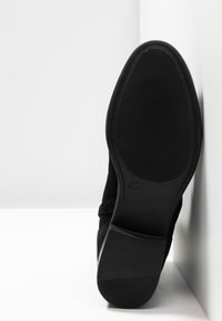 Stivaletto in suede nero con suola in gomma texturizzata. Presenta una punta rotonda e un'altezza di circa 3 cm. Taglia 37 indicata sulla suola.