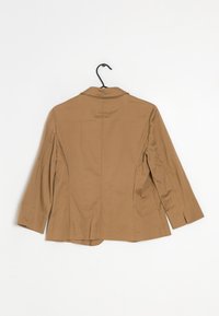 Hnědý, lehký blejzr s výstřihem se zářezem, tříčtvrtečními rukávy a rovnými švy na zádech, zavěšený na černém háčku.