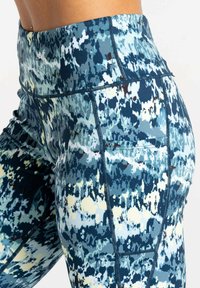 Hochtaillierte Leggings in einem blauen, grünen und weißen abstrakten Muster. Hergestellt aus dehnbarem Stoff mit flachen Nähten und einer Seitentasche.