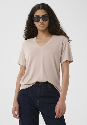 Light pink V-neck T-shirt made of smooth fabric, paired with dark blue denim jeans. Short sleeves and relaxed fit with a simple design.