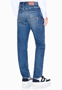 Blaue Jeans aus Denim mit geradem Bein, fünf Taschen, Lederetikett am Bund und sichtbaren Stecknähten.