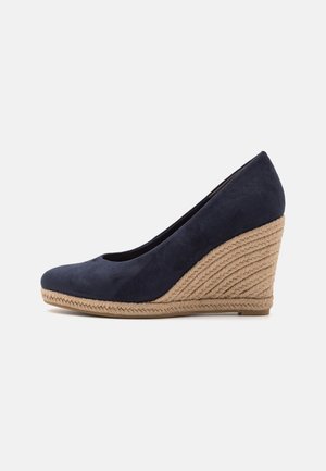 Escarpin wedge bleu marine avec une tige en daim et une plateforme en jute tressé. Design à bout rond et détails texturés sur les côtés.