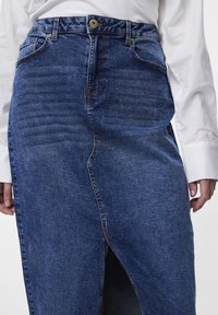 Sötétkék farmer szoknya elől hasítékkal és varrásokkal. Magas derekú, amely gombos záródással rendelkezik a tetején és oldalsó zsebekkel.