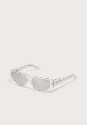 Gafas de sol con montura transparente, lentes grises, diseño angular y patillas estrechas que presentan un sutil acento de logo.