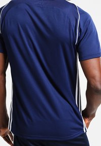 Marinblå idrottströja med vita sidostreck, tillverkad av ett slätt tyg, med rund halsringning och korta ärmar, designad för aktiv användning.