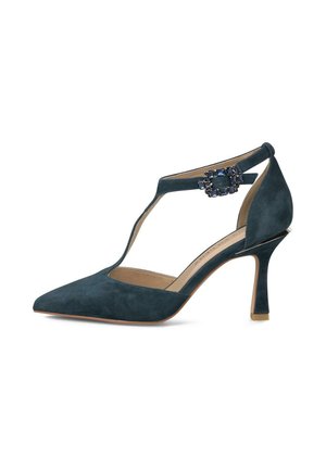 Zapato de tacón alto de ante verde azulado oscuro con punta puntiaguda, tira en T y hebilla decorativa con joyas en la correa del tobillo, tacón delgado inclinado.