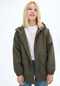 Olivově zelená lehká bunda s kapucí, zipem vpředu, elastickými manžetami a dvěma předními kapsami. Hladká tkanina s volným střihem.