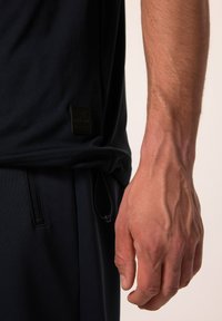 Marinblå atletisk skjorta med en texturerad finish, som har en liten märkesetikett och en justerbar dragsko i botten.