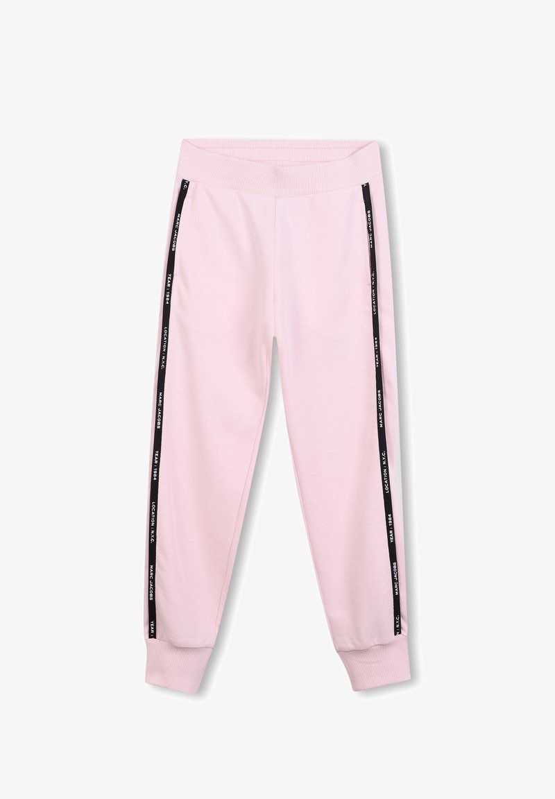 Pantalon de survêtement rose clair avec une taille côtelée et des rayures noires sur les côtés comportant du texte blanc. Fabriqué en matériau doux et extensible.