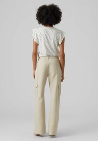 Top bianco con motivo ad occhio di pernice e maniche arricciate abbinato a pantaloni cargo ampi beige chiaro con tasche laterali e vestibilità dritta.