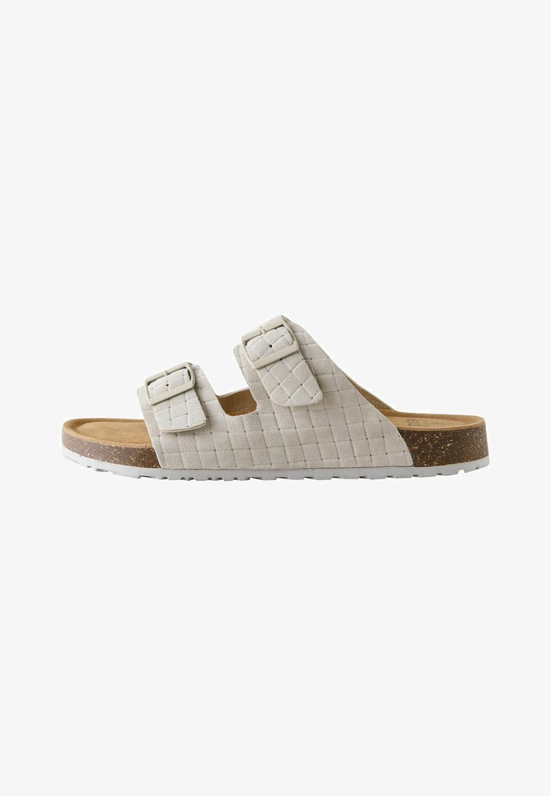 Sandale à glissière beige avec deux brides réglables à boucle, dessus texturé, semelle intérieure en liège et semelle extérieure en caoutchouc blanc.