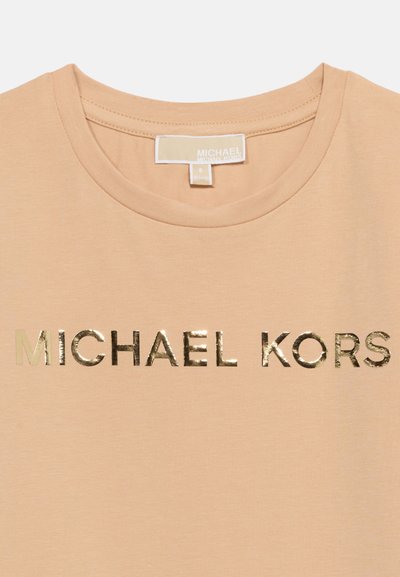 Μπεζ μπλουζάκι με στρογγυλή λαιμόκοψη και λαμπερό χρυσό λογότυπο «MICHAEL KORS» τυπωμένο στο στήθος, καθώς και μπεζ ετικέτα με το εμπορικό σήμα στο εσωτερικό της λαιμόκοψης.