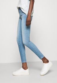 Träningsoverallsbyxor i ljusblå denim, med medelhög midja, smal passform och subtila blekningar. Matcher med vita sneakers och en löst sittande topp.