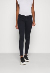 Mörkblå skinny jeans med dragkedjedetalj vid fållen, kompletterade med en smal passform och en klassisk femficksdesign.