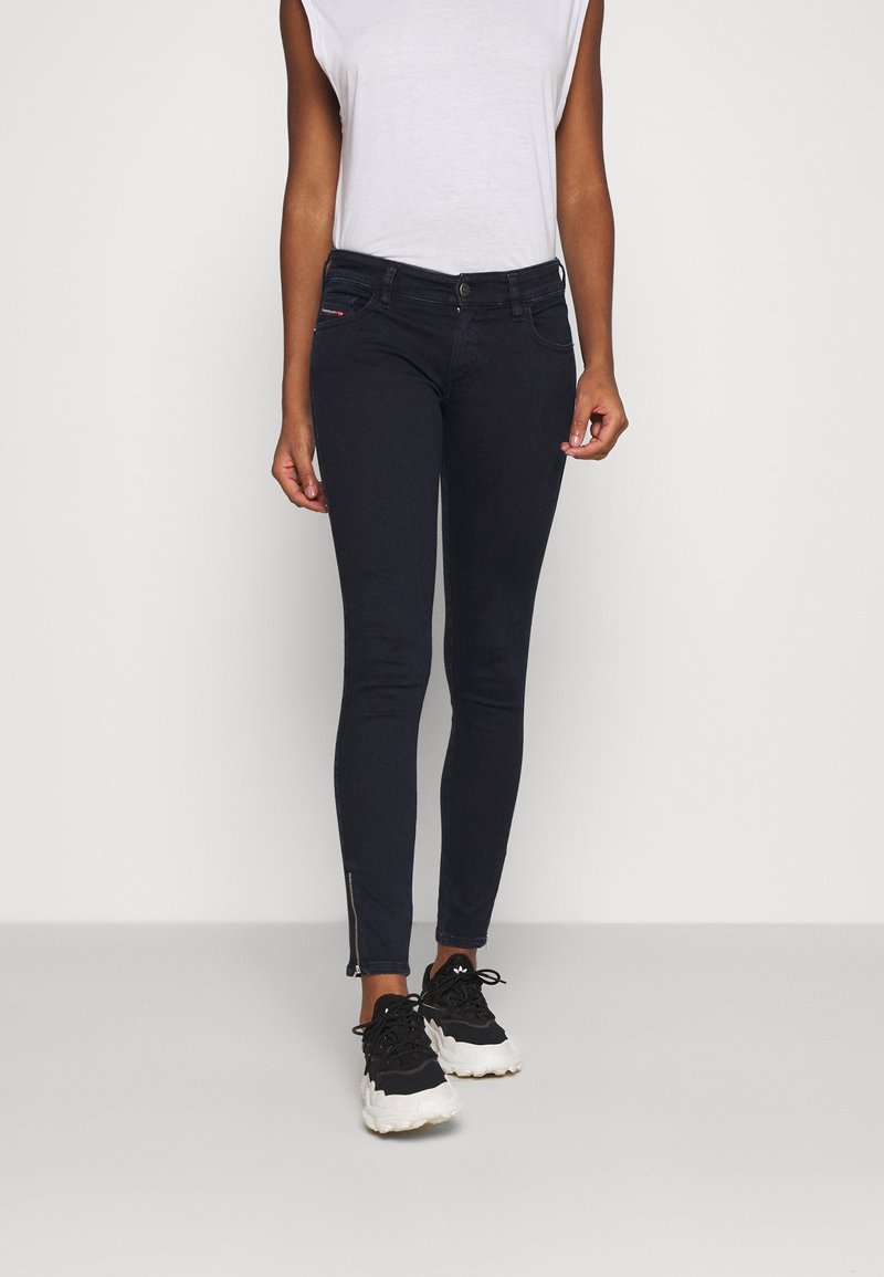 Mörkblå skinny jeans med dragkedjedetalj vid fållen, kompletterade med en smal passform och en klassisk femficksdesign.