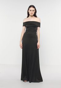 Abito lungo nero scollato sulle spalle in tessuto morbido, con corpino aderente e gonna fluida dal design minimalista.