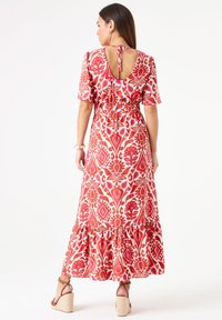 Maxi-jurk met bloemen- en geometrische patronen in rood en roze, korte mouwen, smocked taille, open achterkant en ruches aan de onderkant.