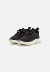 Scarpe da ginnastica nere con una parte superiore in maglia texturizzata, design con lacci e una suola intermedia bianca. Presentano un pratico laccio e accenti in materiale traslucido sulla suola.