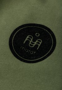 Zielono-oliwkowy materiał z teksturowanym, czarnym okrągłym logo, które zawiera stylizowane litery oraz słowo "marat" na dole.