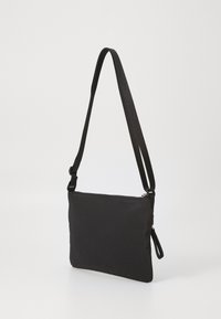Svart nylon crossover-veske med rektangulær form, glidelås og justerbar stropp. Glatt tekstur, minimalisk design, ingen synlige mønstre.