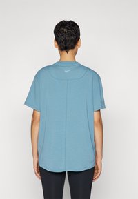 Camiseta azul de manga corta hecha de tela ligera, con cuello redondeado y un pequeño logo de Nike cerca del cuello trasero.
