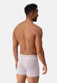 Bóxer blancos de algodón con una suave cinturilla elástica que presenta el texto "DANISH ENDE". Textura suave y diseño ajustado.