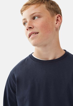 Merinopaitoja pitkällä hihaisella navy sinisellä värillä, jossa on pyöreä kaula-aukko ja teksturoitu kangas. Ominaisuudet yksinkertainen muotoilu ilman kuvioita tai koristeita.