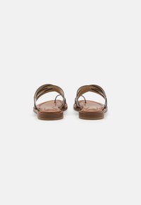 Brown leather sandals with a flat sole, featuring wide cross straps and cut-out details, providing a breathable design suitable for warm weather.