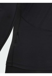 Langermet svart treningsgenser laget av glatt, elastisk stoff med flate sømmer og en tettsittende design, med subtil tekstur og konturlinjer.