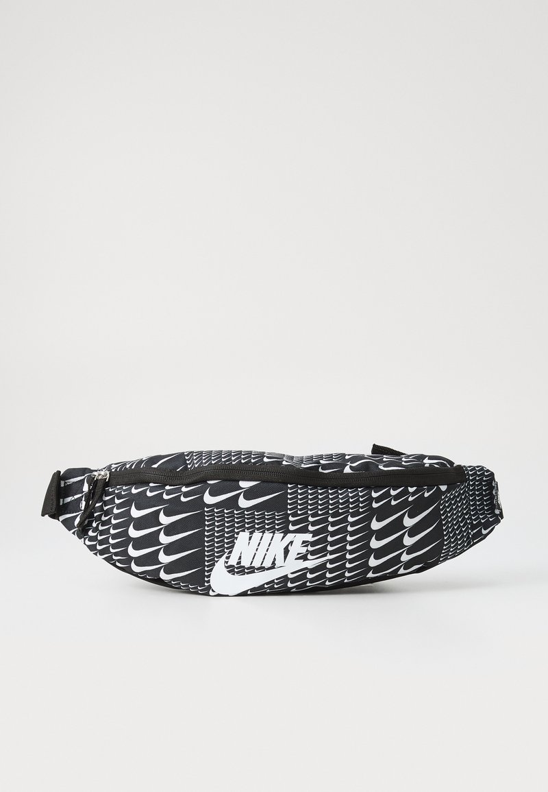 Černobílá ledvinka s opakujícím se vzorem loga Nike, se zipovou kapsou a nastavitelným popruhem. Vyrobeno ze syntetického materiálu a má zakřivený tvar.