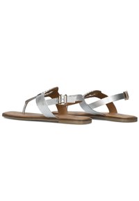 Zilveren platte sandalen met een teenslipperontwerp, metallic banden en een gesp-sluiting. De zool is lichtbruin en plat.