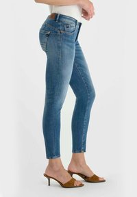 Skinny jeans in mediumblauwe denim met een gladde textuur. Voorzien van zakken, riemlussen en een bruin leren merklabel op de tailleband.