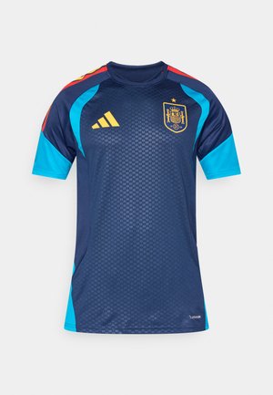 Tumši zila futbola forma ar tirkīza piedurknēm, sarkaniem plecu akcentiem, dzeltenu Adidas logotipu un Spānijas nacionālās komandas emblēmu uz krūtīm.