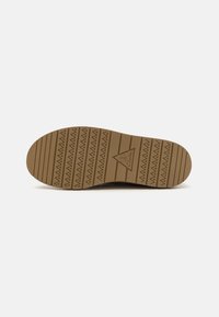 Brown rubber shoe sole with a zigzag tread pattern, embossed logo, and horizontal grooves under a clean white background.