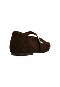 Bruine suède platte schoen met een ronde neus en enkelband, voorzien van een zilveren gespdetail en een strakke, minimalistische stijl.