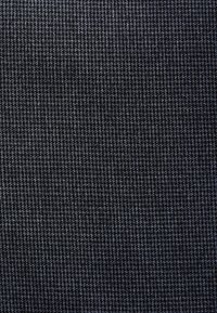 Tissu gris foncé avec un petit motif à carreaux noir et blanc créant un design en grille texturé.