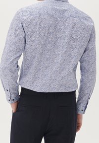 Långärmad skjorta i ljusblått med blommönster i mörkblått och vitt. Har knappärmar, klassisk krage och en smal passform.